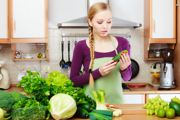 Woman housewife in kitchen with green vegetables