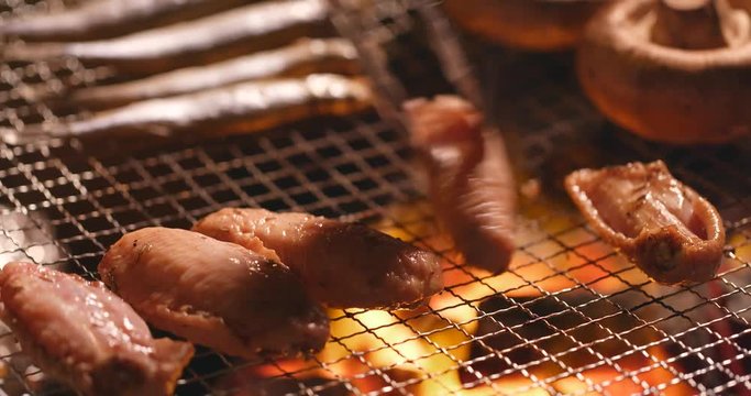 Barbecue with chicken wing, mushroom and capelin fish on grilled net at outdoor