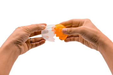 Hands breaking an artificial orange egg isolated on white