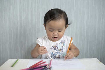 asian toddler / baby girl is having fun learning to use pencils. Education concept. human growth concept.