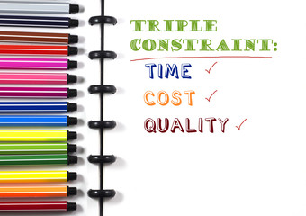Project Management Triple constraint text on white sketchbook with color pen, top view