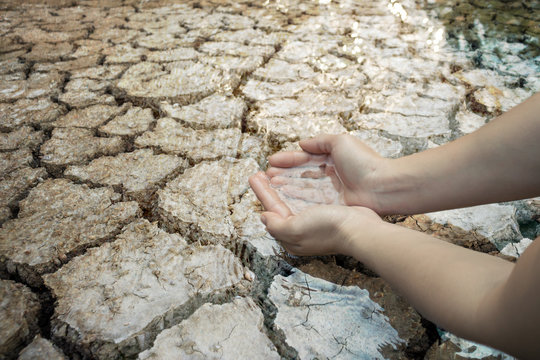 Hand of boy on cracked dry ground, Concept drought and crisis environment.