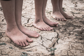 Fototapeta na wymiar Foot of boy on cracked dry ground, Concept drought and crisis environment.