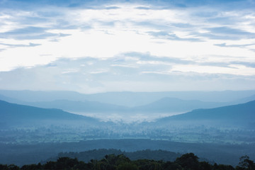 Mountain ridges with silhouette forest in the foreground. Background ridge with spruce forest in the foreground, and layer of hills