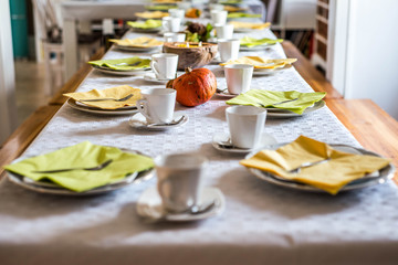 Beautiful festive dinner table colorful yellow fall helloween pumpkin decoration coffee mugs saucers plates and spoons