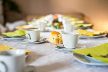 Beautiful festive dinner table colorful yellow fall helloween pumpkin decoration coffee mugs saucers plates and spoons