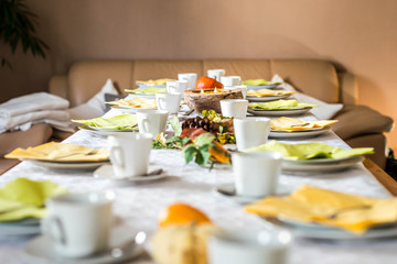 Beautiful festive dinner table colorful yellow fall helloween pumpkin decoration coffee mugs saucers plates and spoons