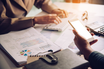Business team working with laptop and smartphone in open space office. Meeting report in progress. sun glare effect