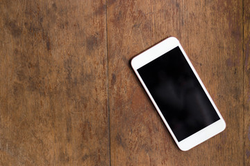 White smartphone on the old wooden background, top view