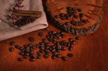 Coffee beans are scattered on a wooden table and burlap