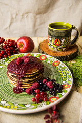 Obraz na płótnie Canvas A pancake on the Christmas table with tea and raspberry jam