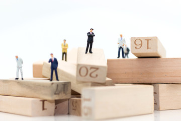 Miniature people : Businessmen standing in various positions of wooden numbers, indicating the sequence of work, used as a business concept.