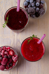 Frozen summer berries smoothie: blueberries, strawberries, raspberries, cranberries, currants and blackberries on wooden background. View from above, top, vertical