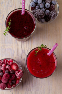 Frozen summer berries smoothie: blueberries, strawberries, raspberries, cranberries, currants and blackberries on wooden background. View from above, top, vertical