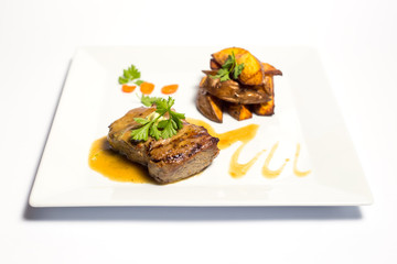 meat with grilled vegetables on a plate on white background