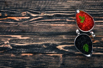 Red salmon caviar and black sturgeon caviar. On a wooden background. Top view. Free space for text.