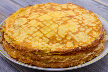 Stack of thin pancakes, crepes on white plate, cup of tea and berry jam