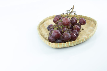 Red grape on the bamboo mat isolated on white background