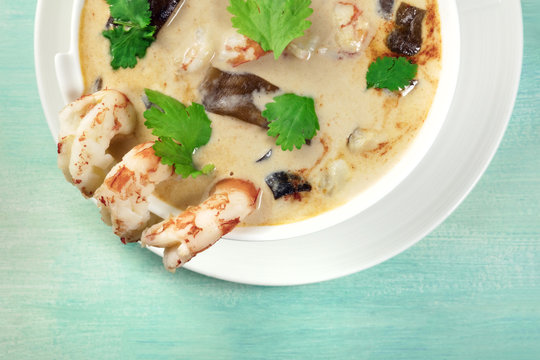 Closeup of Tom Yam, traditional Thai soup with shrimps and mushrooms, on teal