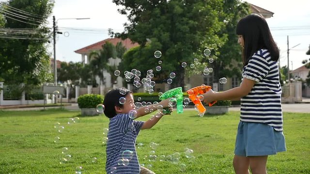 Cute Asian children Shooting Bubbles from Bubble Gun in the park slow motion 