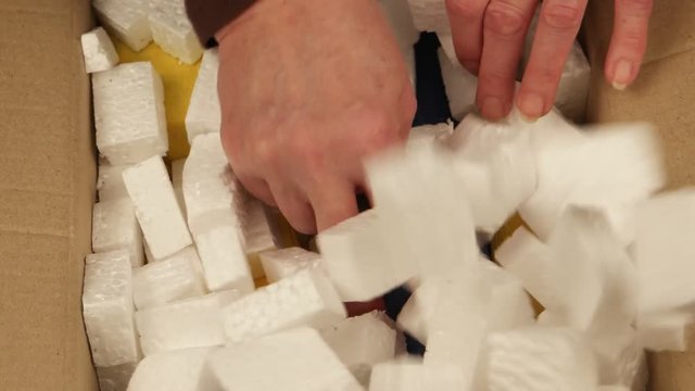 Person opens the  big cardboard carton  and takes out from it the colorful boxes with gifts