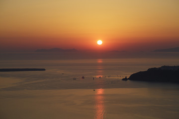 Sunset on Santorini island with some sailboats, Greece