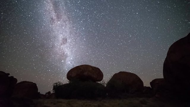a time lapse of the devil's marbles and the milky way at night