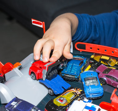 Young boy playing with vintage toy cars at home. Selective focus on hand of boy and toy.