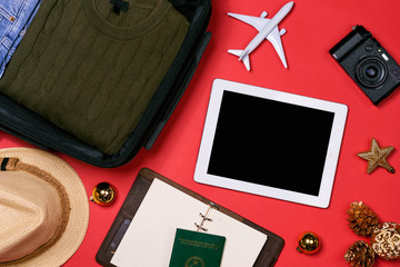 HOLIDAY travel concept - passport, camera, hat, airplane, chrismas decorations on red background