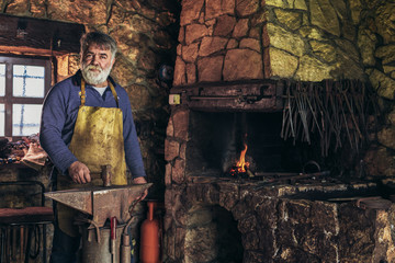 Senior blacksmith forge iron at work
