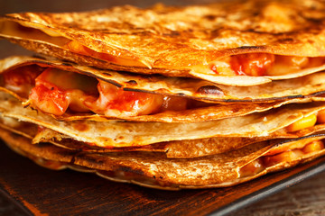 Mexican quesadilla closeup on a plate on a wooden table.