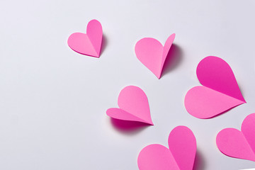 Beautiful pink paper hearts on white paper background