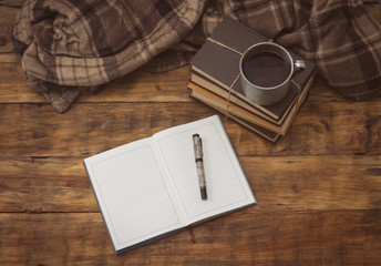 Diary with pen, books, aluminum vintage cup with hot tea and plaid on a wooden background
