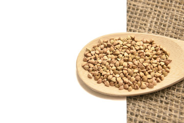 Buckwheat grains. Healthy food. White background. Wooden spoon