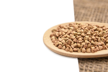 Buckwheat grains. Neutral background. Healthy food. Wooden spoon