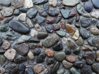 Pebble stone floor tile seamless background. Cement mixed gravel stone floor texture. Wet round pebble stone rock floor with dramatic lighting. Big colorful pebbles on floor after rain near seacoast.