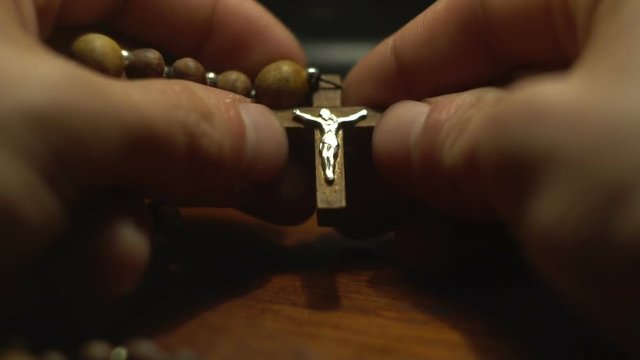 the young man's hands touches the rosary