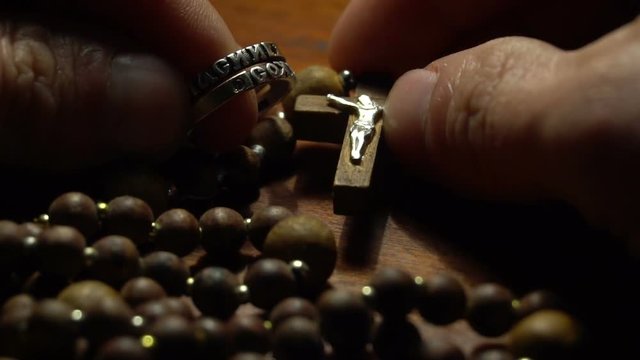 A wooden rosary and ring in the hands of man