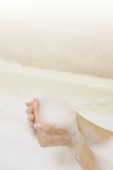 Fototapeta premium バスバブルの泡をすくう女性の手