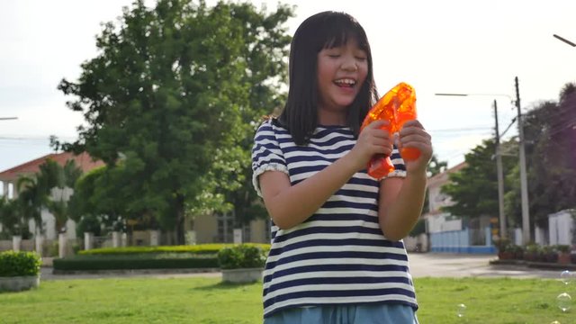 Cute Asian children Shooting Bubbles from Bubble Gun in the park