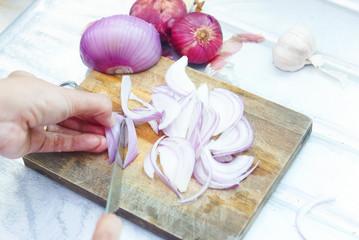 Female Hands Cutting Onions On Chopping Board