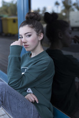 Fototapeta premium Teen girl sitting looking towards the camera. Vertical shot with natural light.
