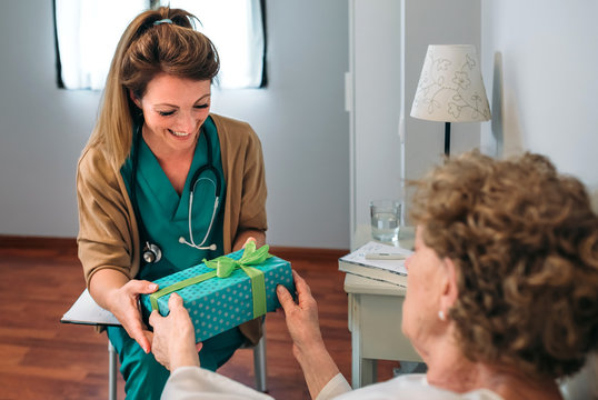 Grateful Senior Female Patient Giving A Gift To Her Female Doctor