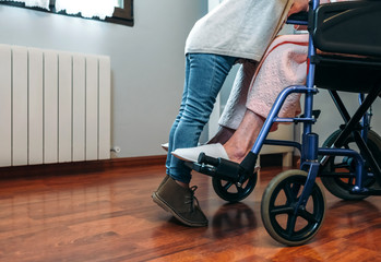 Unrecognizable granddaughter visiting her grandmother in a wheelchair