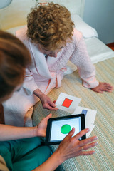 Female doctor showing geometric shape game to elderly female patient with dementia