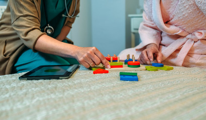 Female doctor showing geometric shape game to elderly female patient with dementia