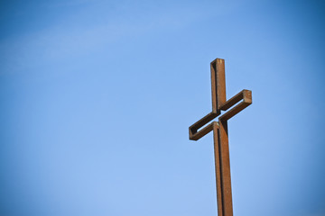 Rusty iron cross against a blue background - Image with copy space