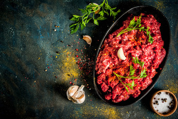 Minced meat with spices and fresh herb on dark table, copy space top view
