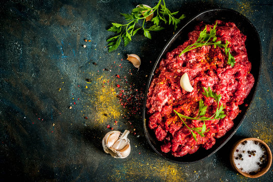 Minced meat with spices and fresh herb on dark table, copy space top view
