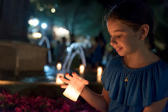 Little girl lit by lit candles during a large celebration in the village square of Navacerrada, Spain.